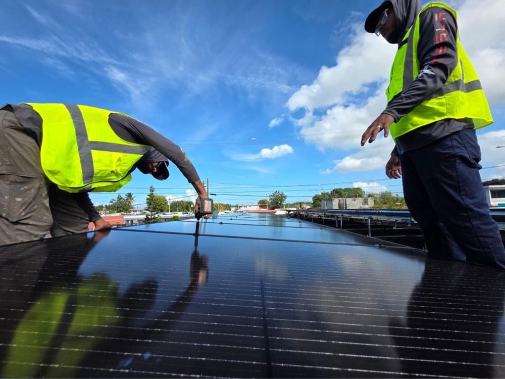 Instaladores colocando paneles solares en un techo en Puerto Rico